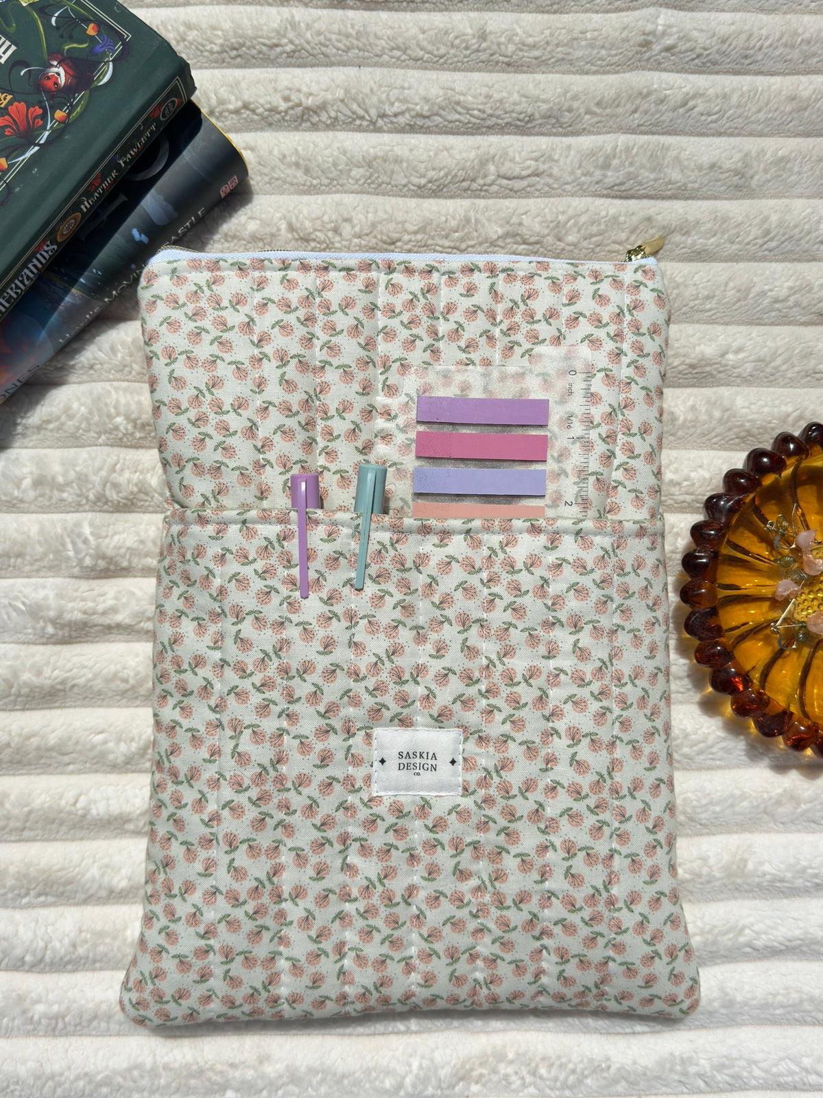 Floral patterned pouch with stationery items on a textured surface